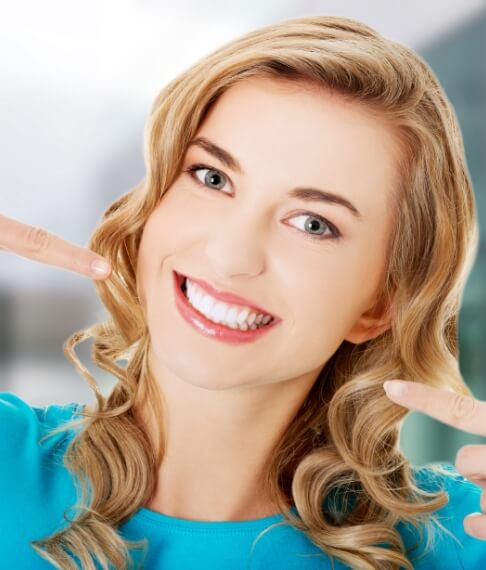 Woman pointing to smile after cosmetic dentistry treatment