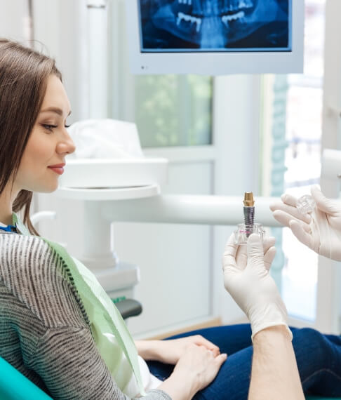 Dentist using model to demonstrate the four step dental implant process