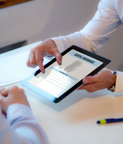 Dentist and patient looking at dental insurance forms on tablet computer