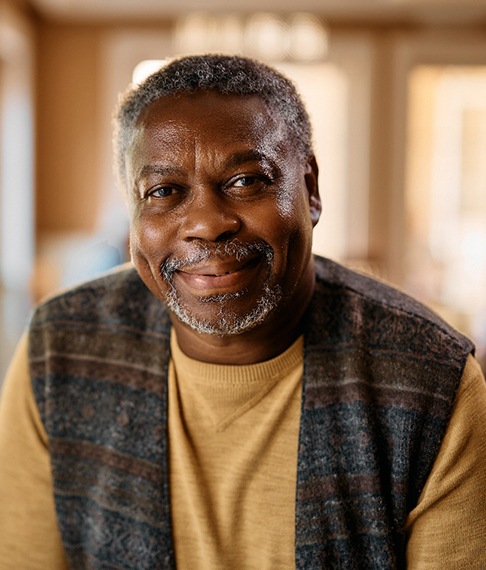 Closeup of man in plaid vest smiling at home