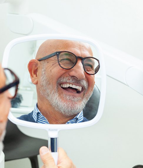 Man with black glasses smiling in reflection in mirror