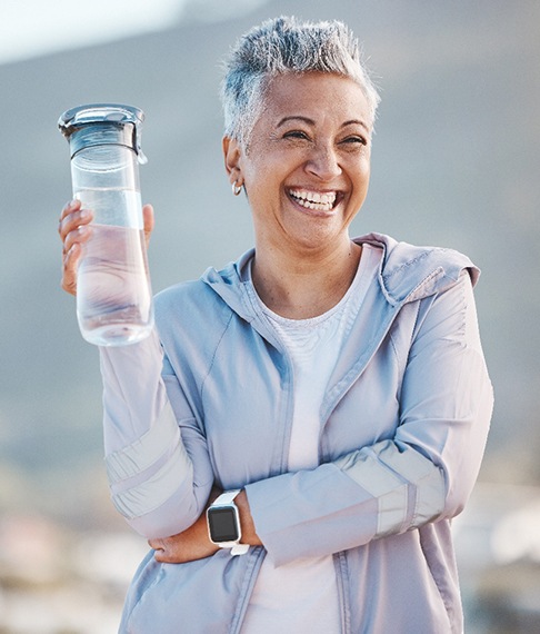 Woman smiling with water bottle on hike outside