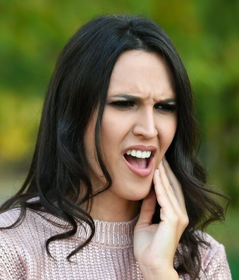 Woman in need of emergency dentistry holding jaw