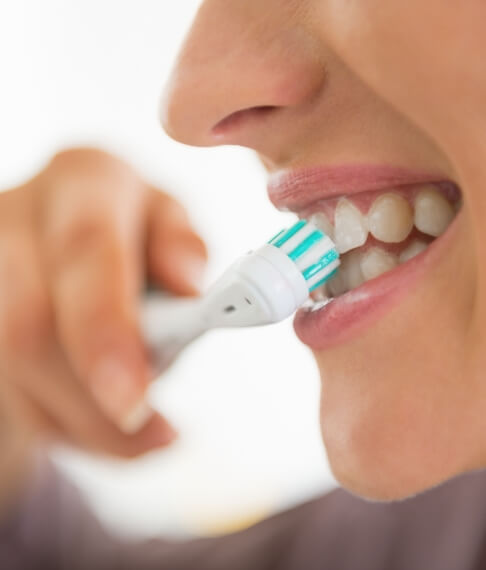 Patient brushing teeth to prevent dental emergencies