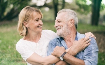 Man and woman smiling after replacing missing teeth