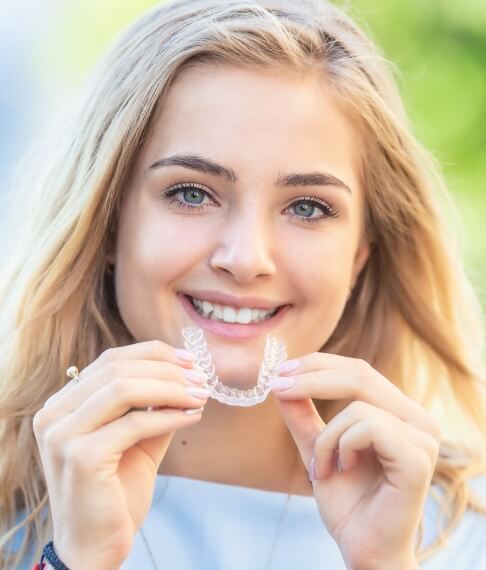 Smiling woman placing her Invisalign clear braces tray