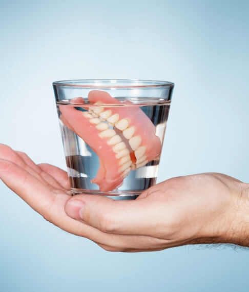 Full set of dentures in a glass of water