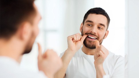 man flossing in bathroom