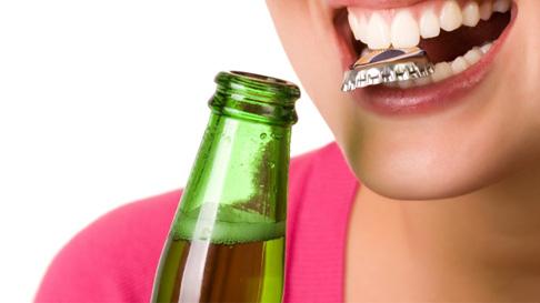 woman opening bottle with teeth 