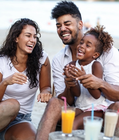 Parents and child laughing together after receiving dental services