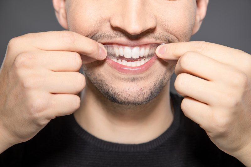 A man applying a teeth whitening strip to his smile